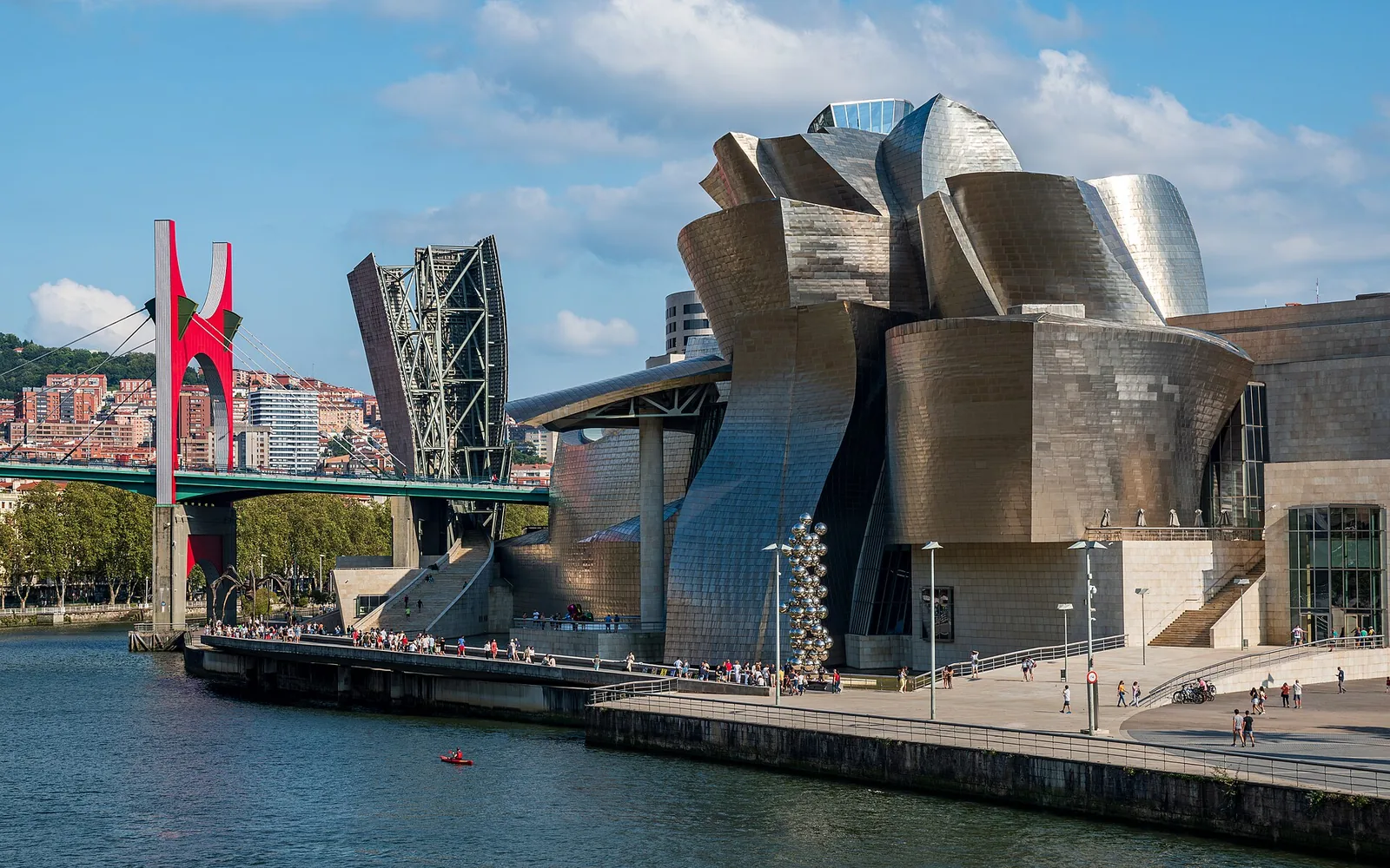 Guggenheim Museum Bilbao from Northwest. Three sculptures from the museum's collection can be seen outside: Tulips by Jeff Koons, Tall Tree